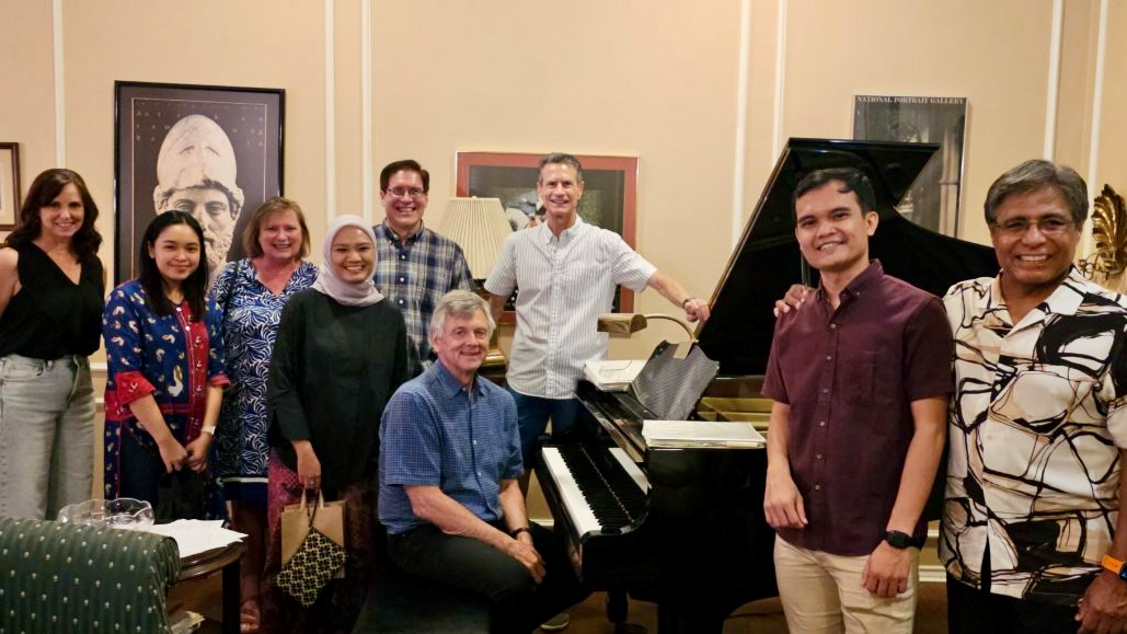 IVLP participants and their Dinner Diplomacy hosts posing for a picture by a piano.